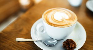 Cup with hot tasty coffee on wooden table in cafe, close up